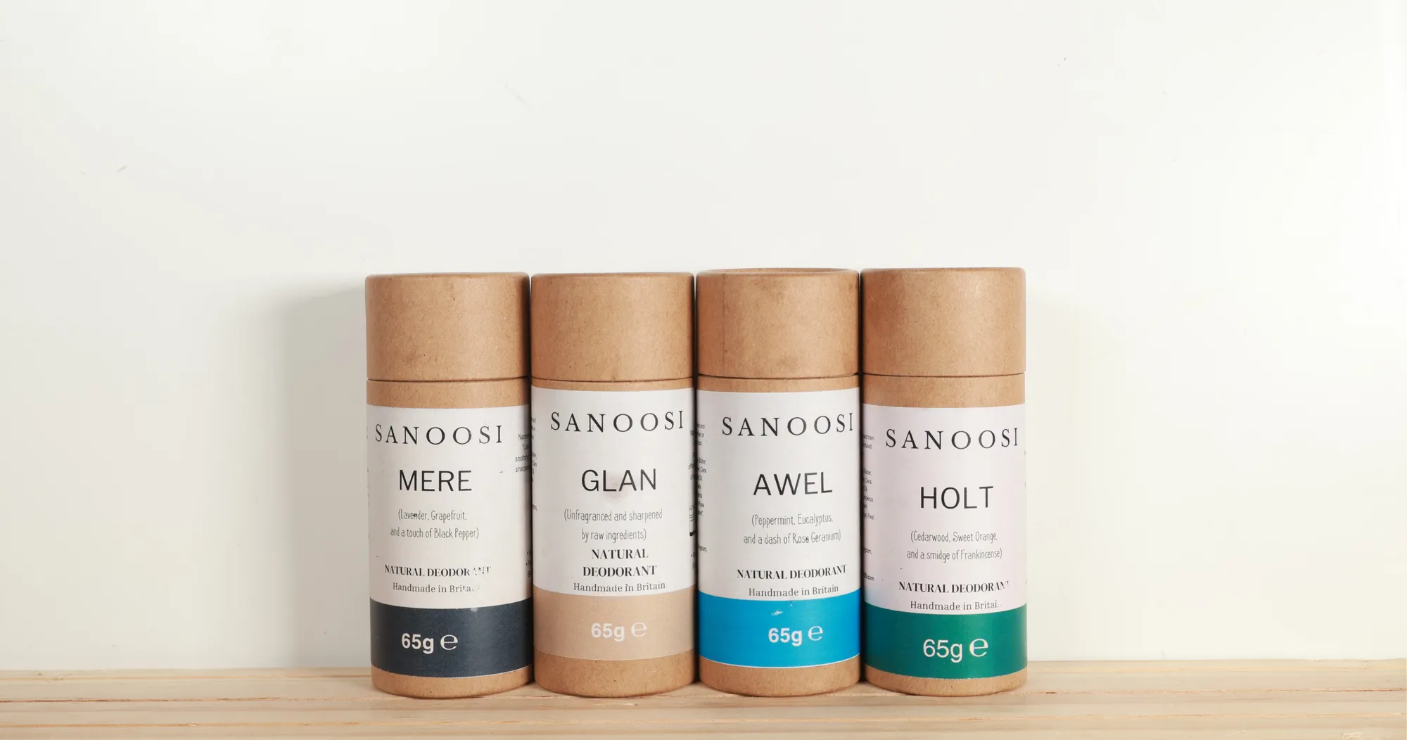 Four SANOOSI natural deodorants in MERE, GLAN, AWEL and HOLT, standing on a wooden shelf